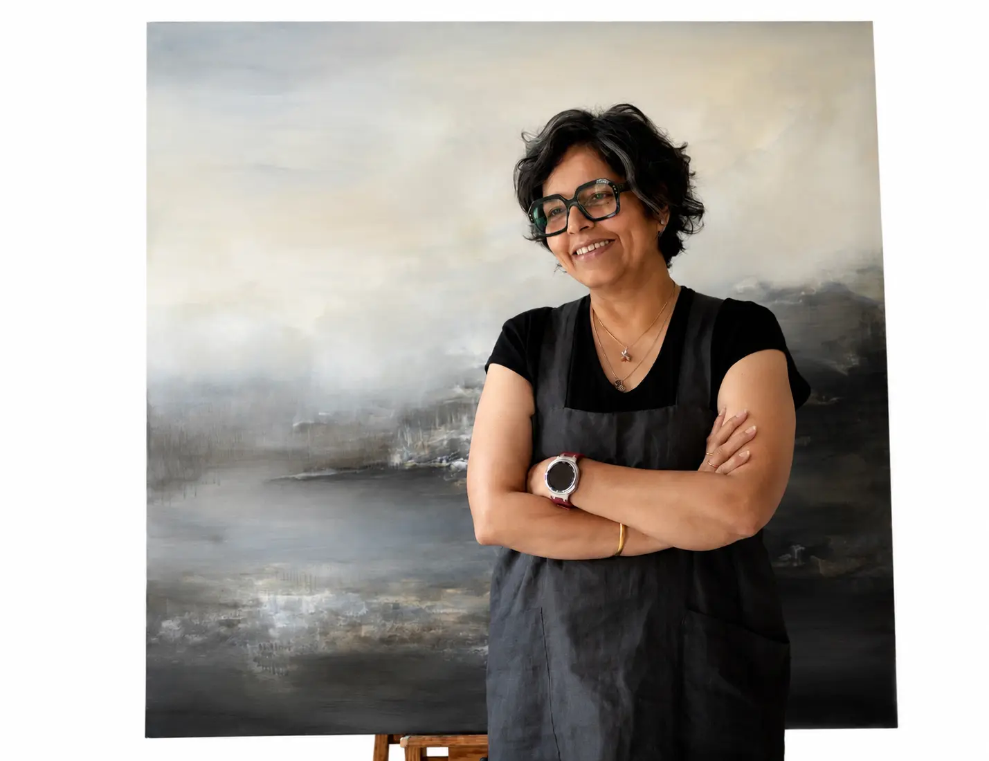 Reena Yadav Ramakrishnan in her studio, before a large landscape painting